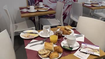 Un desayuno con croissants, pastelería y una bebida de café en una mesa.