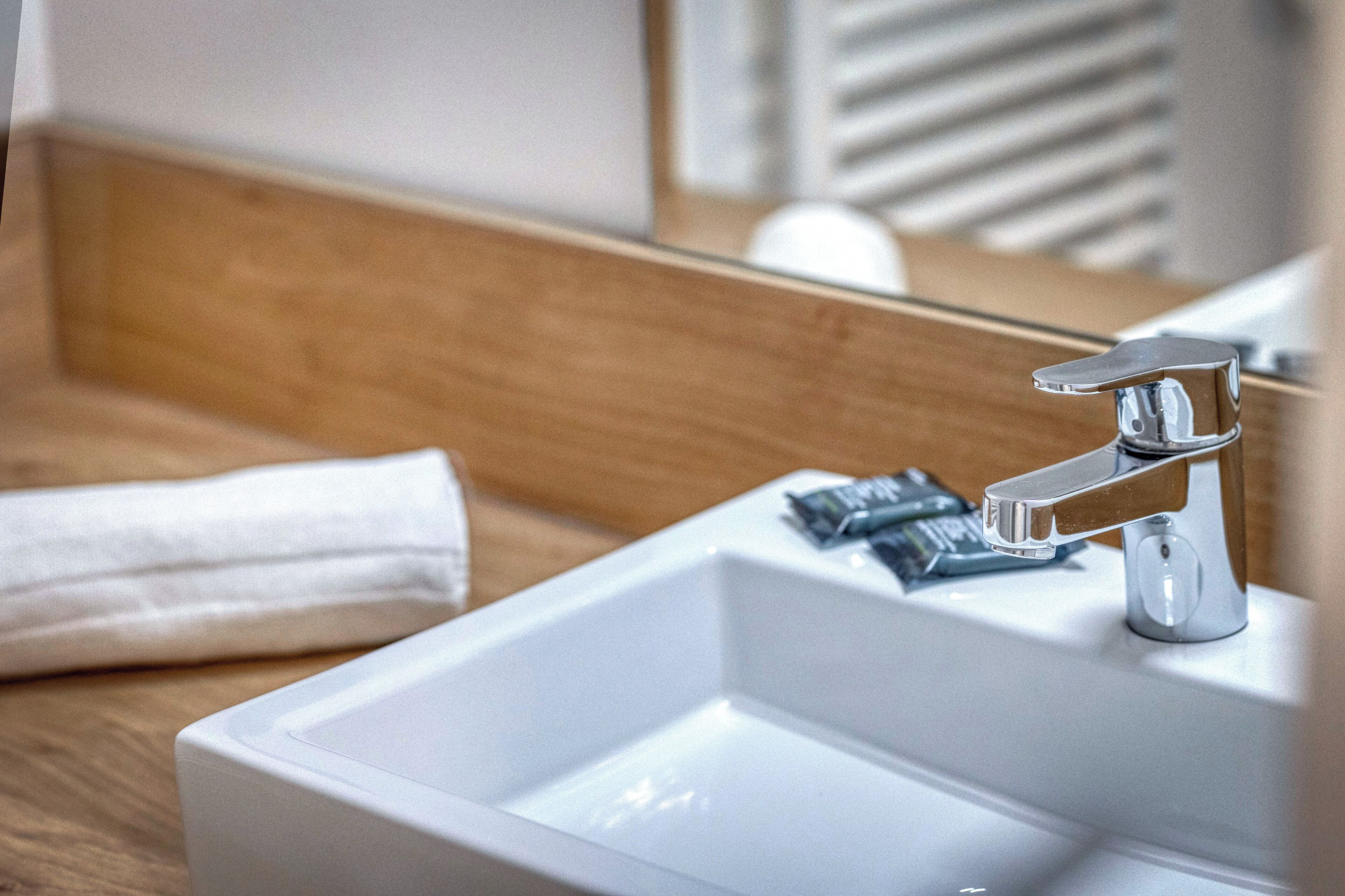 A bathroom with a white sink, a mirror, and a towel on the counter.
