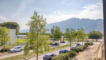 A parking area with multiple cars, trees, and a mountain in the background.