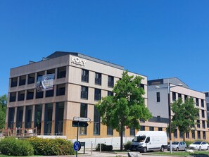 A modern building with a sign for 'KOSY' and a 'TOUTES DIRECTIONS' sign.