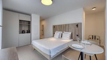 A modern bedroom with a bed, bedside table, and a round dining table with chairs.