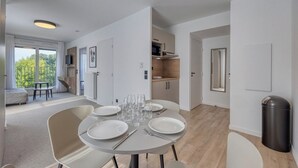 A modern, open-plan living space with a dining area, kitchen, and a balcony with a view.