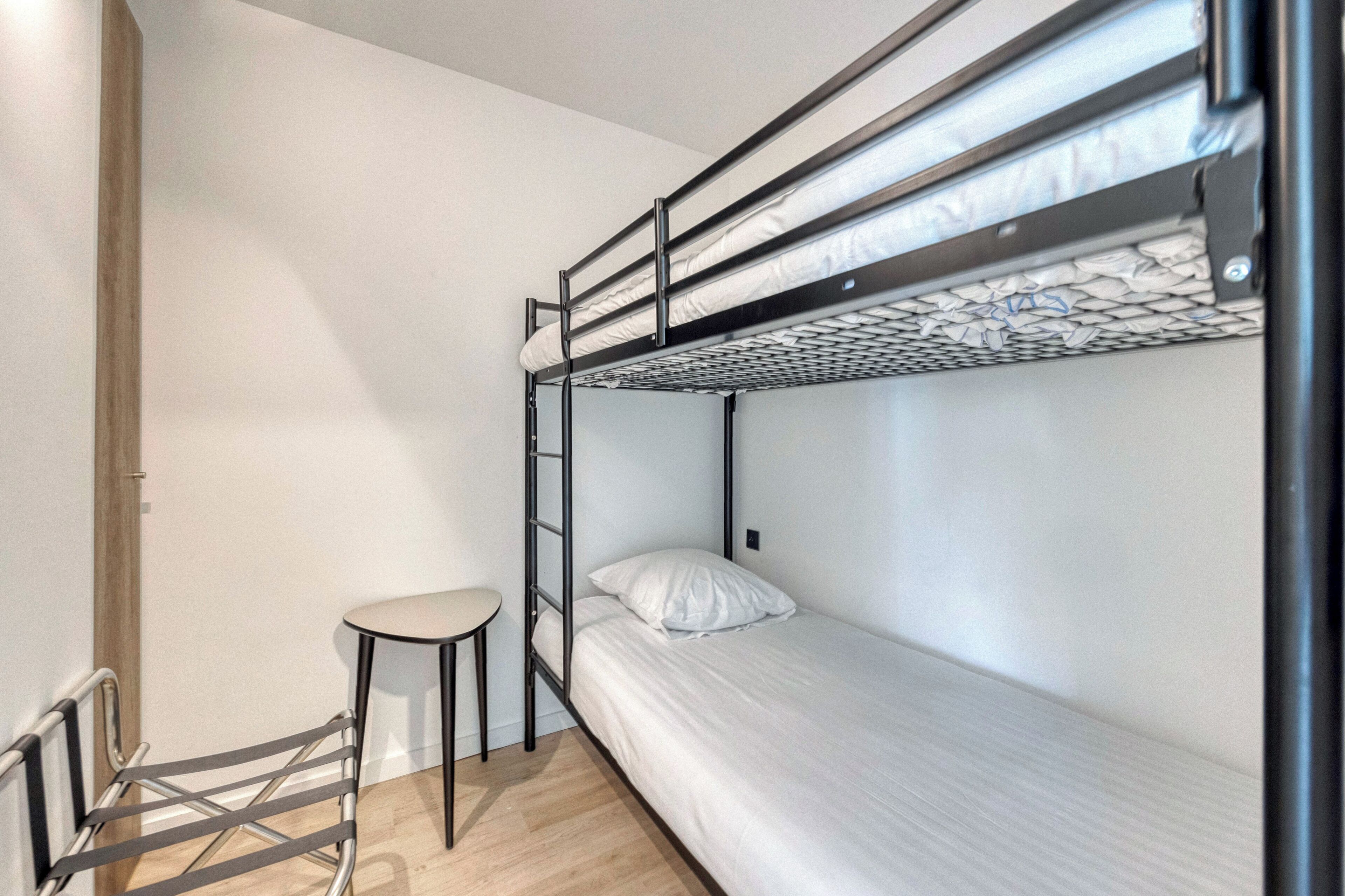 A bunk bed room with a small table and a ladder.