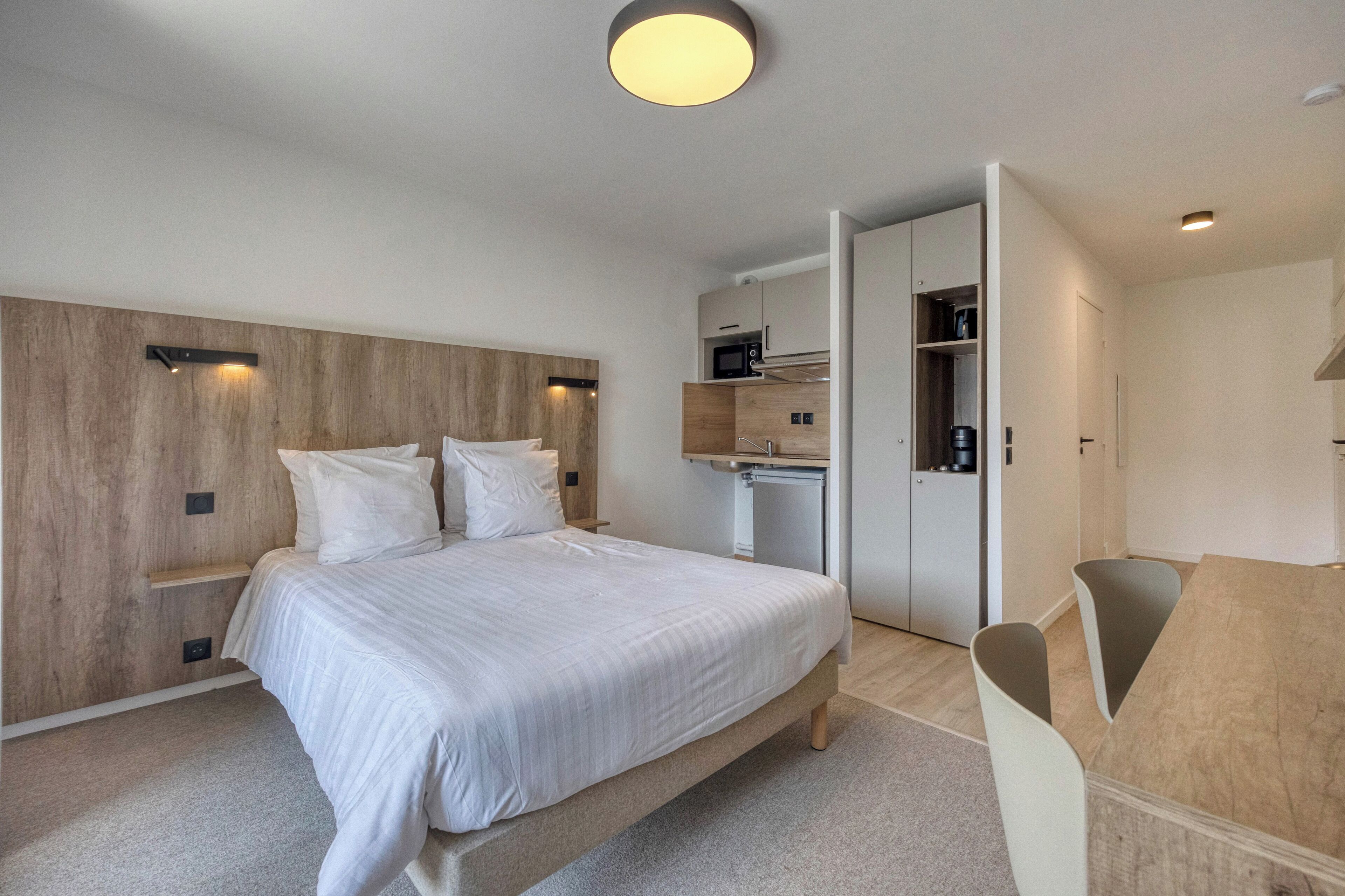 Un dormitorio moderno con una cama grande, estanterías empotradas, un escritorio y un armario.