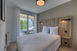 A modern bedroom with a large bed, a wooden headboard, and a view of the outdoors.