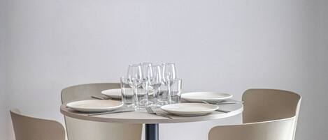 A round dining table with six chairs, a framed abstract artwork on the wall, and a clean, minimalist decor.