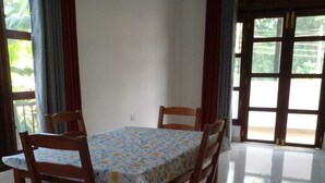 A dining area with a table covered by a floral tablecloth, surrounded by wooden chairs. - Villa in Yakkala, Gampaha (Yakkala)