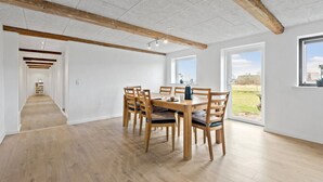 A spacious dining area with a wooden table and chairs, white brick walls, and a view of the outdoors through a large window. - Stunning home in Ribe with Wi-Fi (Ribe)