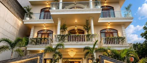 A multi-story hotel with a grand entrance, multiple balconies, and a well-lit facade.