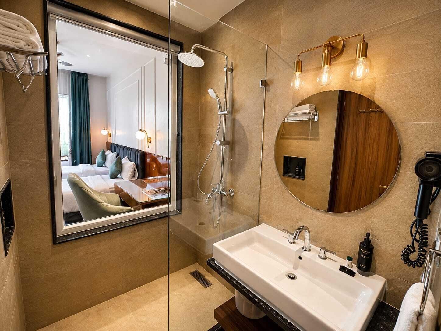 Un baño moderno con cabina de ducha de vidrio, un espejo grande y un lavamanos blanco.