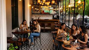 Un café con mesas y sillas, un suelo estampado y luces colgantes.