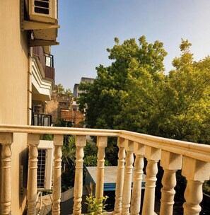 A balcony with a balustrade overlooking a residential area with trees and buildings. - Hotel Rio Benaras (Varanasi)