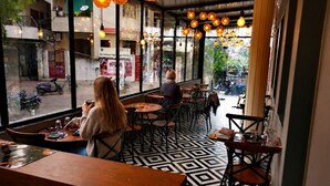Un café con piso de patrón geométrico, mesas redondas y lámparas esféricas colgantes.