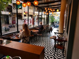 Un café con piso de patrón geométrico, mesas redondas y lámparas esféricas colgantes.