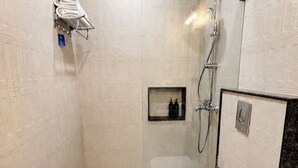 Un baño pequeño y moderno con ducha, inodoro y lavabo.