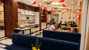 Un restaurante con mostradores de mármol, asientos tapizados en azul y globos rojos y blancos.