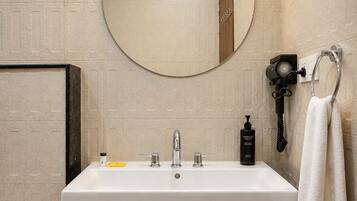 A bathroom with a white sink, a round mirror, and a towel rack.