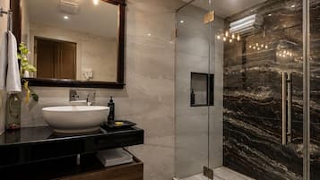 A modern bathroom with a large mirror, a white sink, and a glass-enclosed shower.