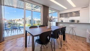 A modern kitchen with a large window, a dining area with a wooden table and chairs, and a view of the cityscape. - Phaedrus Living: City Center Luxury Flat N. Kosmos (Athina)
