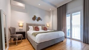 A modern bedroom with a large bed, a chair, a nightstand, and a wall-mounted light fixture. - Phaedrus Living: City Center Luxury Flat N. Kosmos (Athina)