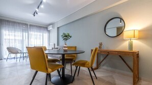 Un comedor con una mesa redonda, cuatro sillas, una mesita auxiliar de madera, un espejo y una lámpara.