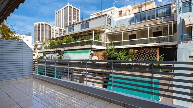 Un edificio residencial con balcón, piscina y vistas a otros edificios.
