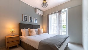 Un dormitorio con cama, mesitas de noche, lámpara y ventana con cortinas.