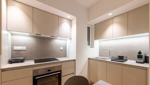 A compact kitchen with integrated appliances, a dining area with a table and chairs, and a small window for natural light. - Phaedrus Living: Executive Flat Kolonaki (Athina)