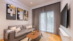 A modern living room with a grey sofa, a wooden coffee table, and abstract art on the wall. - Phaedrus Living: Executive Flat Kolonaki (Athina)