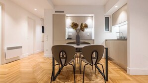A modern dining area with a wooden herringbone floor, a round table, and four chairs. - Phaedrus Living: Executive Flat Kolonaki (Athina)