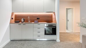 A modern kitchen with white cabinetry, a wooden countertop, a built-in oven, and a sink. - Phaedrus Living: Luxury Flat Panormou (Athens)