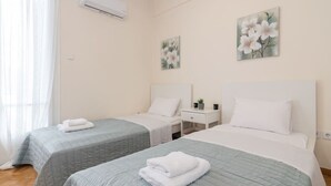 A hotel room with two beds, a nightstand, and a wall-mounted air conditioner.