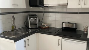 A modern kitchen with white cabinets, a black countertop, a microwave, a toaster, and a sink.