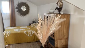 A bedroom with a bed, a wooden dresser with decorative items, and a mirror on the wall.