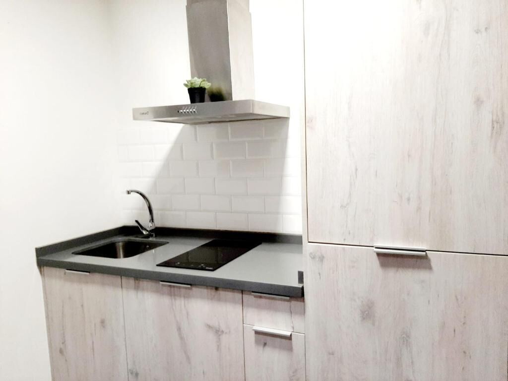 A kitchen with a black countertop, a sink, and a stainless steel range hood.
