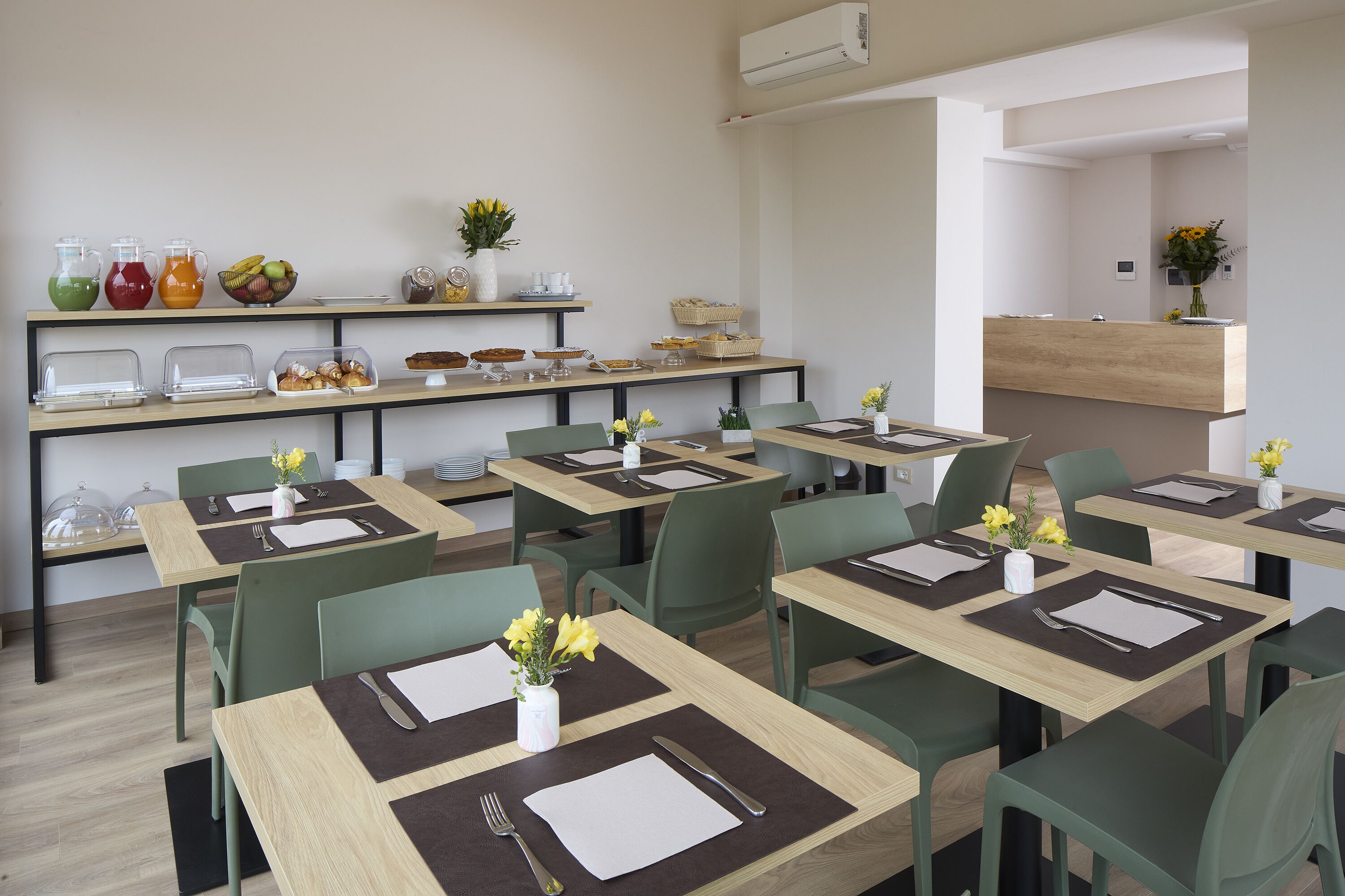A modern dining area with multiple tables, chairs, and a buffet counter.