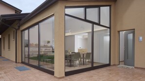 A modern building with large glass doors leading to an interior space with a dining area and a kitchen. - Luci di Assisi B&B Wellness (Assisi)