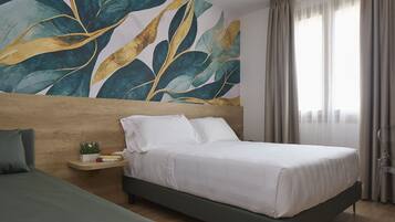 A modern hotel room with a large bed, a nightstand with a plant, a wooden headboard, and a large abstract painting on the wall.