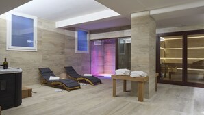 A modern spa area with a skylight, lounge chairs, a sauna, and a wooden table with towels. - Luci di Assisi B&B Wellness (Assisi)