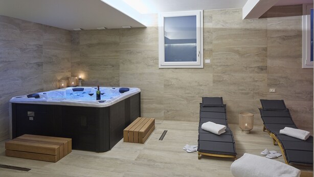 A spa room with a hot tub, wooden benches, and a framed picture on the wall. - Luci di Assisi B&B Wellness (Assisi)