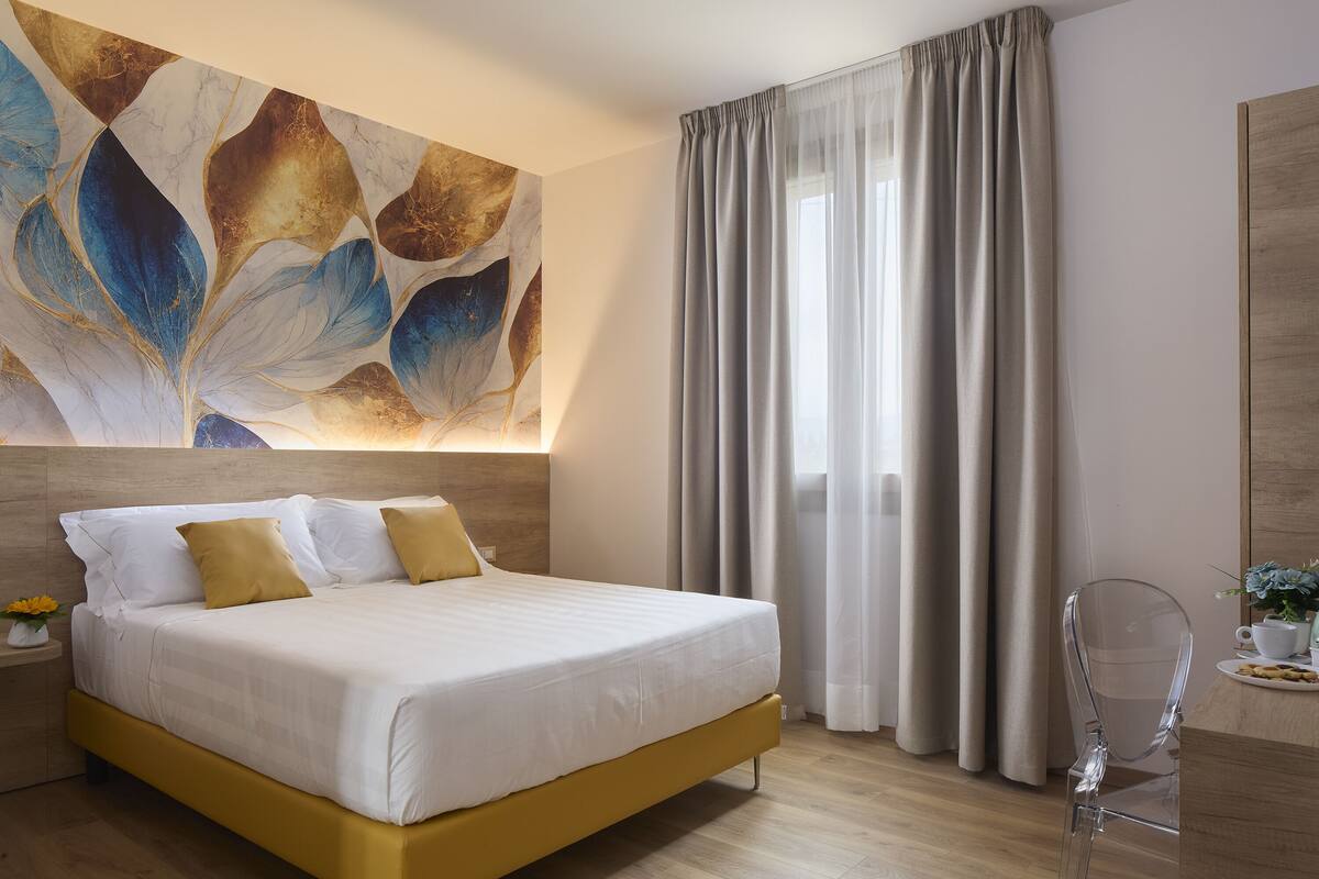 A modern bedroom with a large bed, a clear chair, and a wall art piece.
