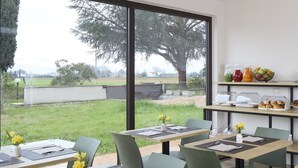 A dining area with large windows, a view of a grassy yard, and a breakfast bar with fruit and pastries. - Luci di Assisi B&B Wellness (Assisi)