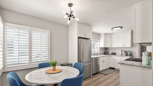 A modern kitchen with white cabinetry, a marble island, and blue chairs. - Ocean Views w/ Private Ground Floor Patio | Fire Pit (San Diego)