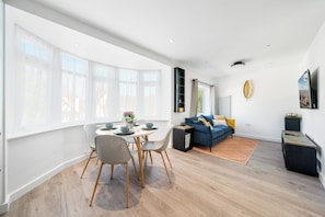 En moderne stue med spiseområde, store vinduer og udsigt over byen.