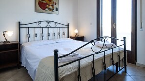 Un llit ben fet amb un panell de capçal acolxat, una làmpada de nit i un quadre a la part superior.