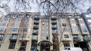 A multi-story hotel with a modern architectural design, featuring balconies on each floor, a prominent entrance with a sign, and a white van parked in front. - Seattle's Gem: Elegant 1BR in Belltown - Sleeps 4 (Seattle)