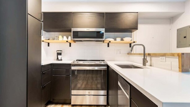 A modern kitchen with stainless steel appliances, a microwave, oven, and dishwasher. There is a wooden countertop and a sink with a faucet. - Seattle's Gem: Elegant 1BR in Belltown - Sleeps 4 (Seattle)