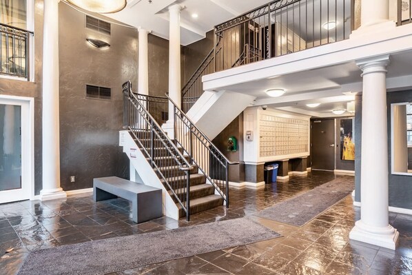 A spacious interior with a grand staircase, a large open area with a tiled floor, and a wall of mailboxes. - Seattle's Gem: Elegant 1BR in Belltown - Sleeps 4 (Seattle)
