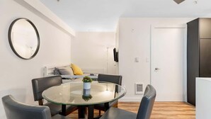 A modern living room with a glass dining table, leather chairs, a round mirror, and a ceiling fan. - Seattle's Gem: Elegant 1BR in Belltown - Sleeps 4 (Seattle)