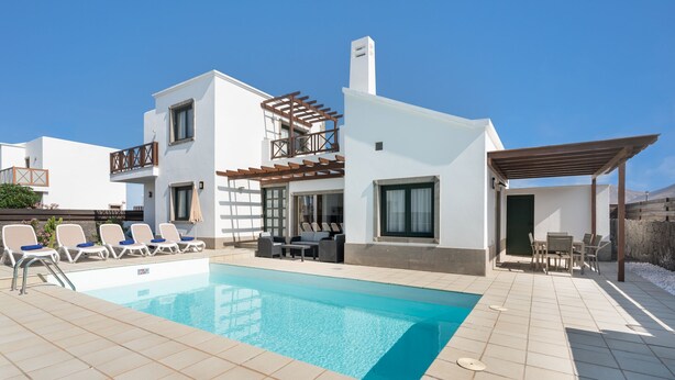 Eine moderne Villa mit Schwimmbad, Sitzgelegenheit im Freien und einer Pergola.